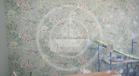 Обои с яркими цветами как нельзя лучше подошли к гладким серо-зелёным стенам гостиной.