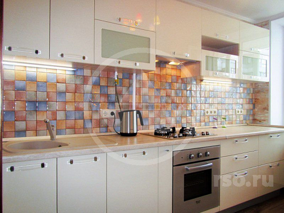 Современная кухонная мебель светлых тонов чудесным образом гармонирует с рассыпанными яркими пятнами брызгозащитного фартука и совместно с окружающими обоями на стенах создаёт индивидуальный дизайн.